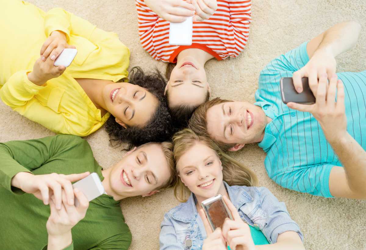 group of teens using phone | Best iPhone Apps Free Of Charge | best iphone apps free | must-have iphone apps