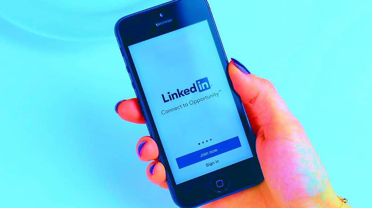 Holding mobile phone | How To Delete LinkedIn Account In Just A Few Easy Steps | Simple LinkedIn Guide