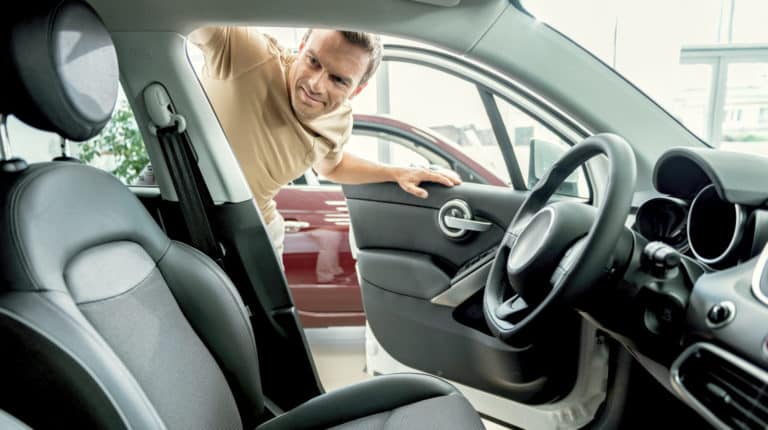 Featured | Smiling man looking car interior | AutoTempest Used Car Finder | Overview And FAQs