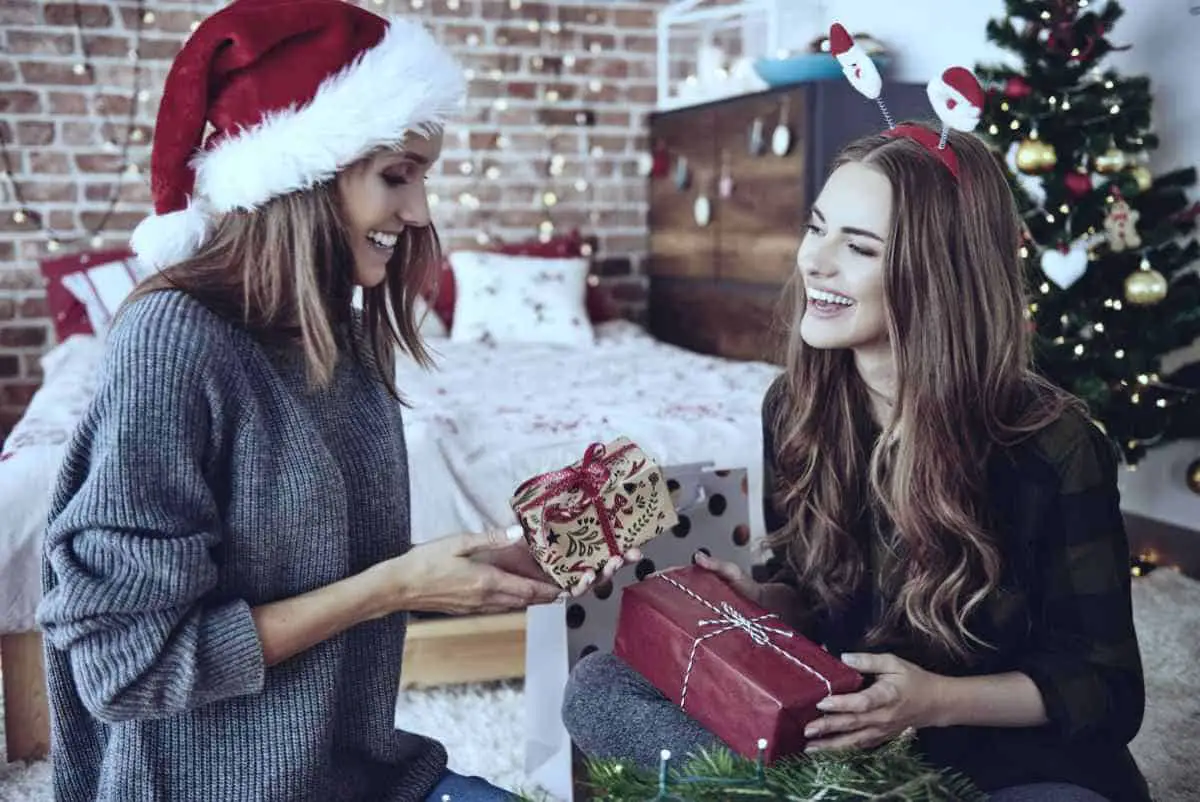 two women exchanging gifts | Smart Christmas Shopping Tips To Help You Stick To A Budget