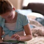 Feature | Girl sitting on bed holding tablet | Best eBooks on Kindle for Kids