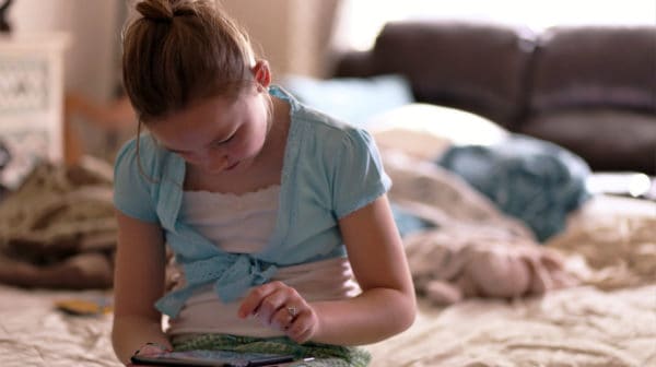 Feature | Girl sitting on bed holding tablet | Best eBooks on Kindle for Kids