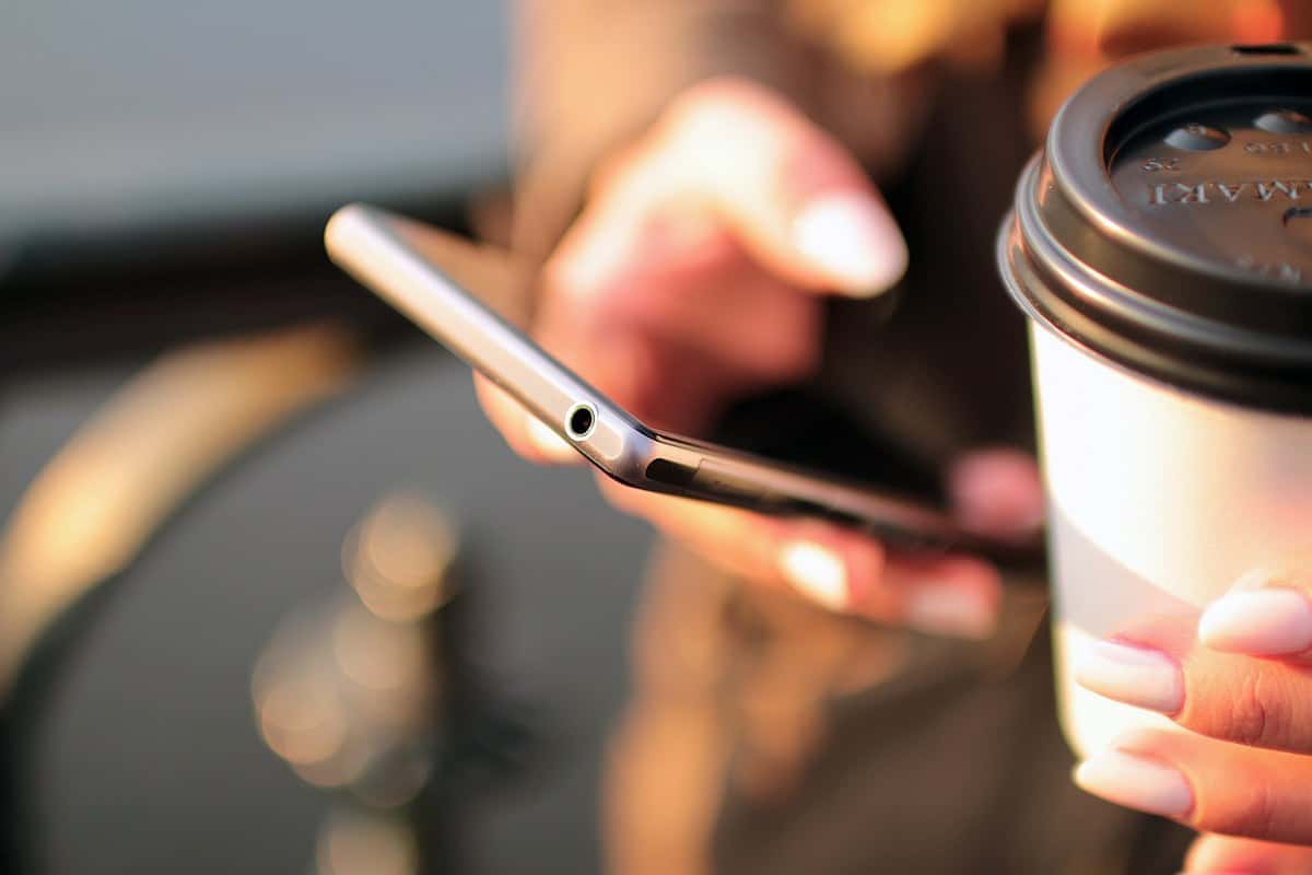Holding Mobile phone and coffee | Location Tracking On Smartphones: How Does It Work?