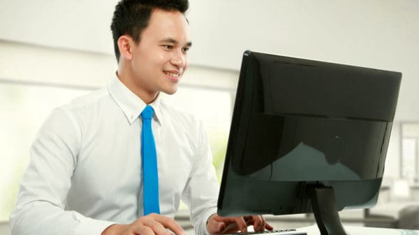Feature | Portrait of a young business man smiling with computer in the office | How To Recover Unsaved Word Documents On Your Computer