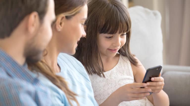 Feature | Smart funny preschooler girl sit on couch together with young parents | Best Free Parental Control App To Keep Your Kids Safe From Online Dangers