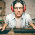 Feature | Young man with headphones and cap playing game | Video Game Tester Jobs: How To Get Paid To Play Video Games