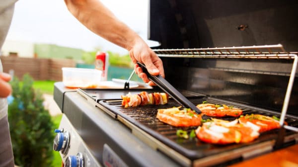 Featured | Hand of young man grilling some meat and vegetable | Best Outdoor Grills on Amazon Under $200 | Outdoor Grill